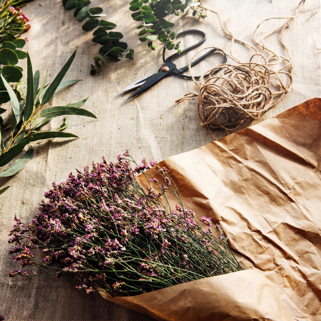 AI-generiertes Stillleben: Floristik-Flatlay mit Trockenblumen und Werkzeug